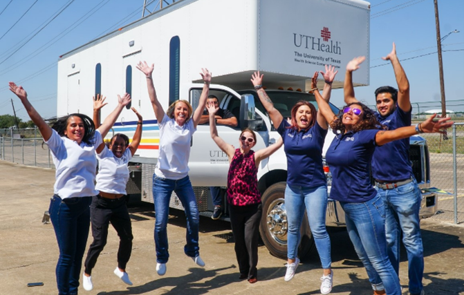 Image of health staff posing in front of a white medical services van.