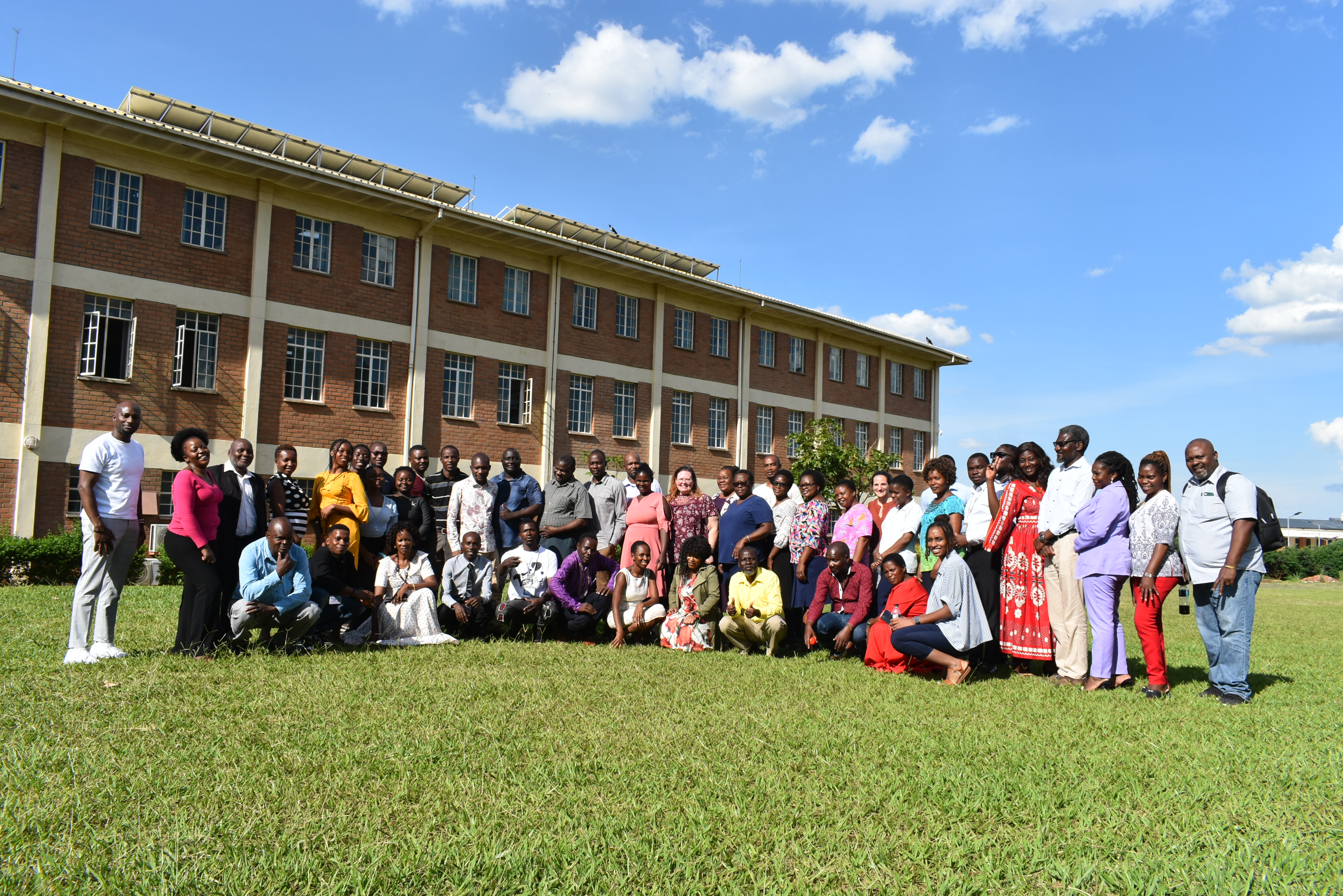 Image of the HPTN 112 study members posing for a photo outside on grass during a sunny day.