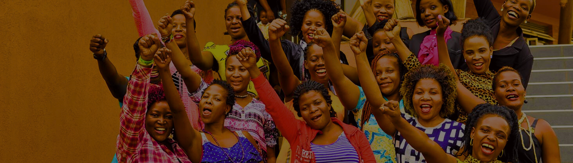 A group of women raise their hands in celebration.